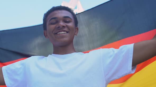 Afro-American teenager boy waving German flag outdoors