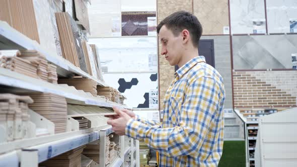 Young Man Chooses Tiles in a Hardware Store Slow Motion