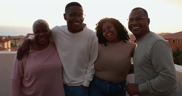 Happy african family looking and smiling in camera on patio outdoor at sunset