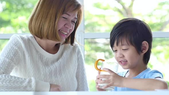 Asian Mother Giving Milk Drink To Her Son
