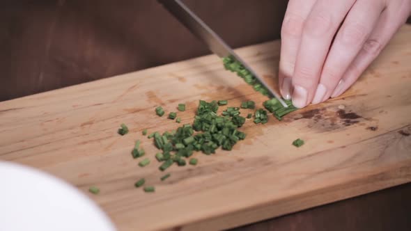 Step by step. Chopping fresh chives on cutting board for garnishing American style creamy mashed pot