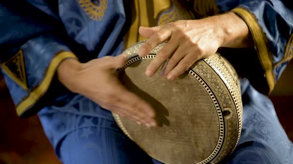 Tight shot of man in Moroccan dress playing arabic doumbek, darbuka, or derbeki