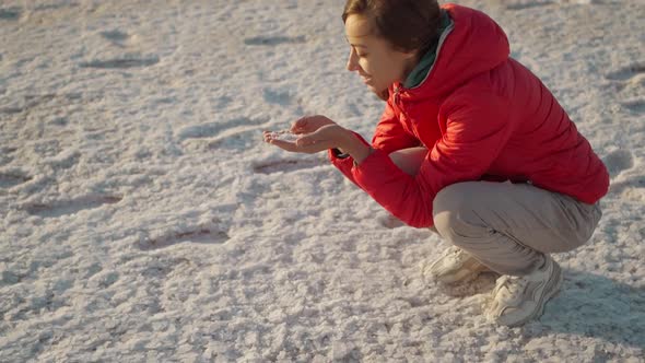 Woman in Red Jacket Smiling and Holding Salt Crystals in Hands at Beautiful Landscape of Salt Flats