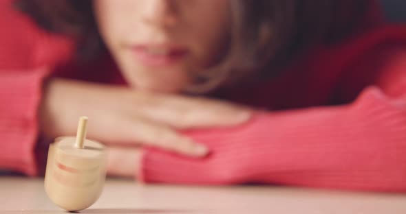 Close up shot of a girl spinning a Hanukka dreidel on the floor