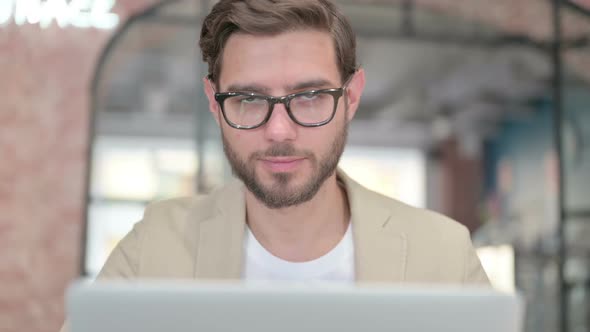 Close Up of Man with Laptop Smiling at Camera