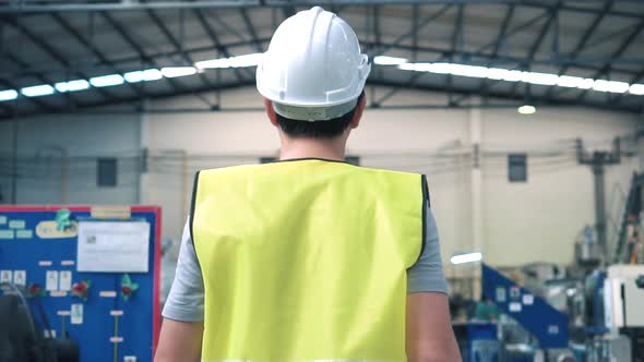 Factory Worker with Safety Hard Hat Walking Through Industrial Facilities