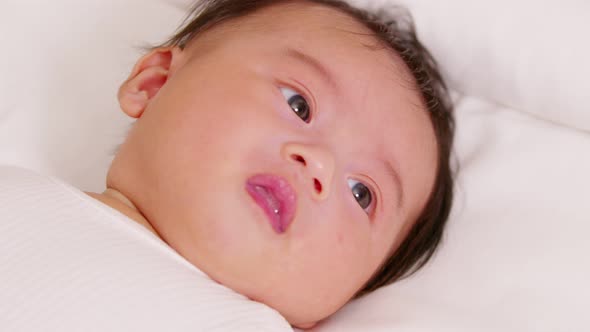 happy newborn baby lying on a white bed and blanket comfortable and safety