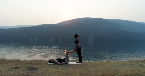 Women practicing acroyoga near lakeside 4k