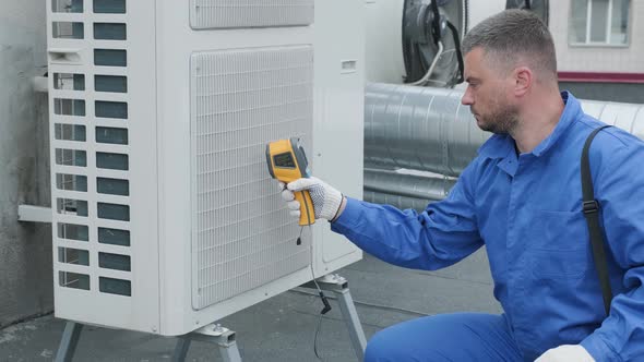 Technician uses a thermal imaging infrared thermometer to check the condensing