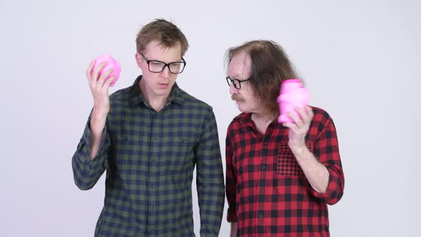 Senior Hipster Man and Young Hipster Man Shaking Piggy Banks Together