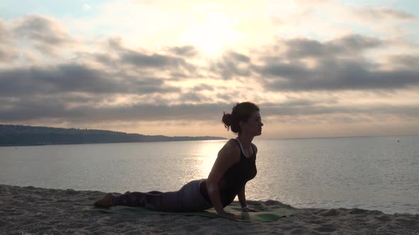 Woman practicing yoga on the beach. Outdoors sports. Healthy living. Sunrise