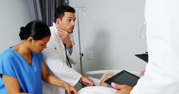 Doctors examining senior patient in ward