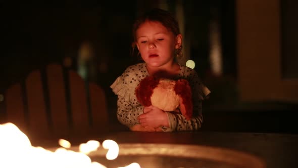 A young girl enjoys a camp fire with her best friend a stuffed puppy.