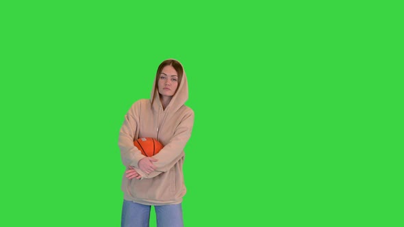 Young Sporty Girl Dancing in a Casual Way with Basketball Ball in Hands on a Green Screen Chroma Key