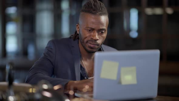 Portrait of Concentrated Confident African American Handsome Man Sitting in Restaurant Bar Messaging