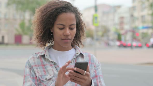 African Woman Browsing Internet on Smartphone Outdoor