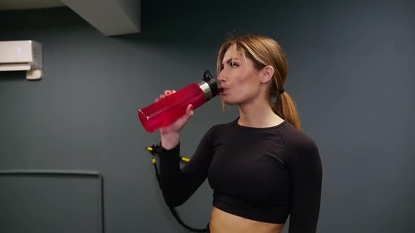 Woman drinking water from bottle after gym.