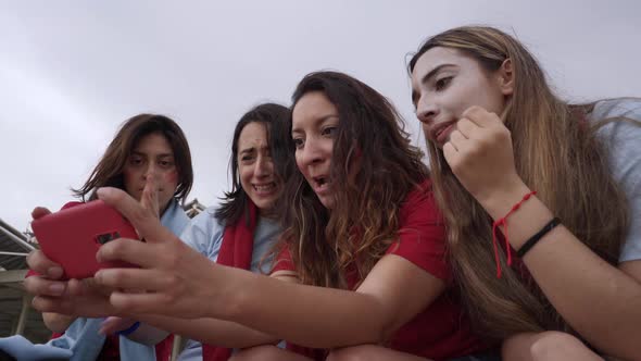 Group of Female Followers of a Soccer Team Watching a Match on Streaming Dressed in Red Tshirts
