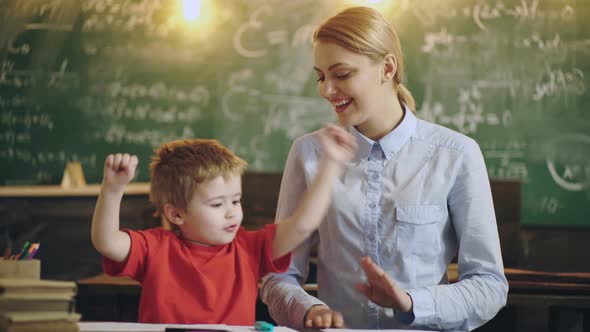 Smiling Teacher Helping a Little Student at the Elementary School