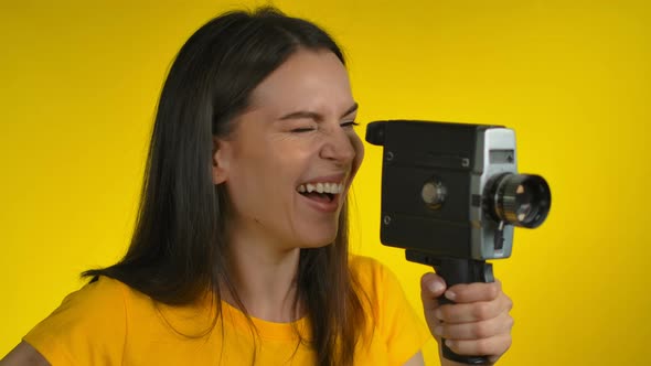 A Cheerful Darkhaired Woman is Using a Retro Camcorder for Shooting Video