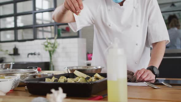 Caucasian female chef teaching diverse group wearing face masks