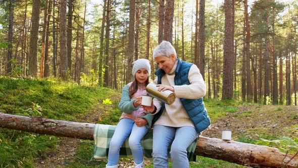 Grandma with Granddaughter Drinking Tea in Forest