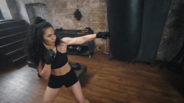 Young Woman Practices Kicking Punching Bag with Fists