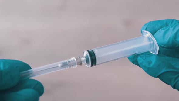 Nurses Hands Holding an Injection Syringe in Latex Nitrile Blue Gloves