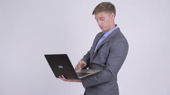 Young Handsome Businessman Talking While Using Laptop