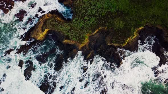 Waves swirl around rocky cliffs on the California coast at sunrise