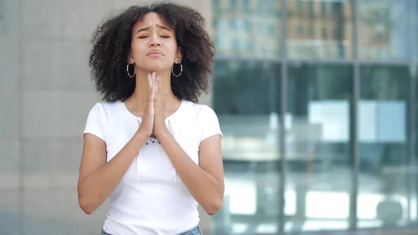 Young Afro American Woman Makes Wish, Crossing Middle and Index Fingers on Hands, Prays Clasped