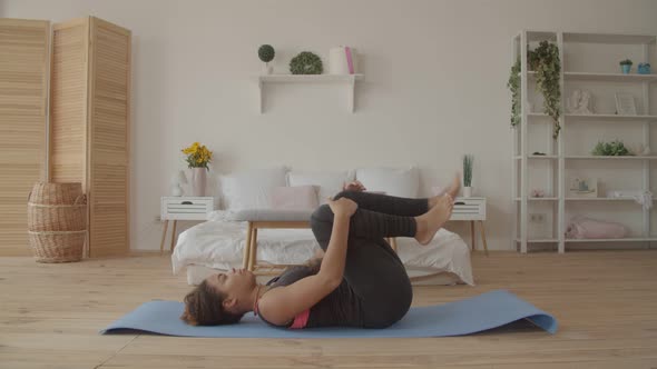 Fit Black Woman Doing Knees To Chest Pose Indoors