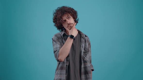 The Young Curlyhaired Hipster Thinks Looking to the Right with His Hand on His Chin