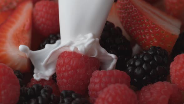 Strawberry, blackberry and raspberry in a bowl pouring with milk. Slow Motion.