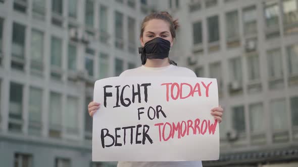 Beautiful Woman in Face Mask Standing in Urban City with Banner and Looking at Camera