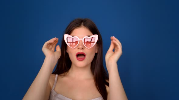 Portrait of a Beautiful Girl in Pink Glasses on a Blue Background