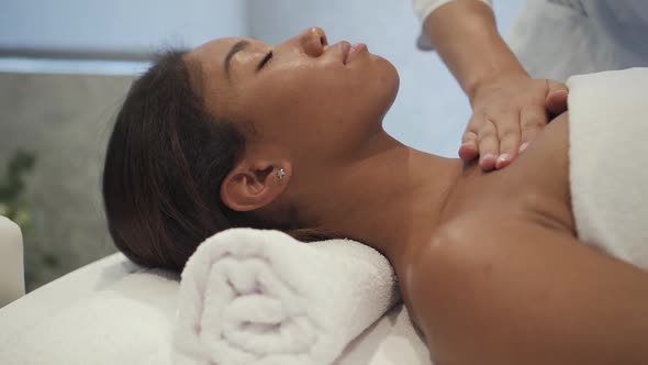 Therapist Massaging Shoulders of African Customer in Spa Center