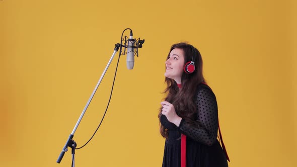 A woman in classical dress at the recording studio sing lyrical song into a microphone