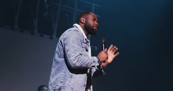 African American Man Speaks Into a Microphone While Standing on Stage