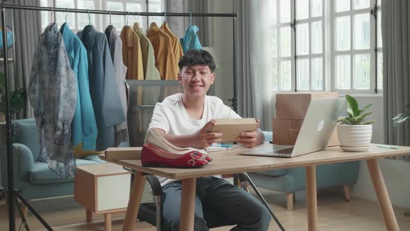 Man Online Seller With Package Look At Camera And Smile While Using Computer For Selling Online