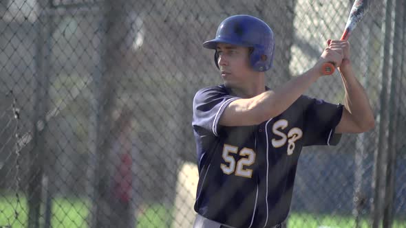 A young man practices baseball at the batting cages.