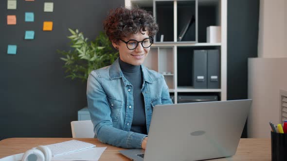 Cheerful Girl Busy with Laptop Work in Office Typing and Looking at Screen Smiling