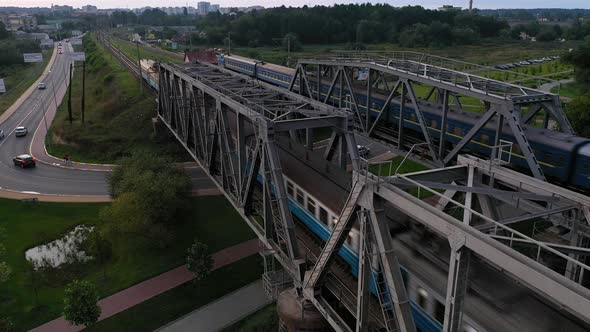 Two trains traveling opposite each other on a railway bridge from aerial view.