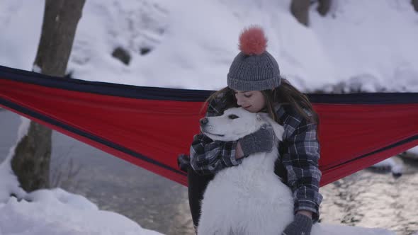 Woman sitting in hammock holding and petting her dog