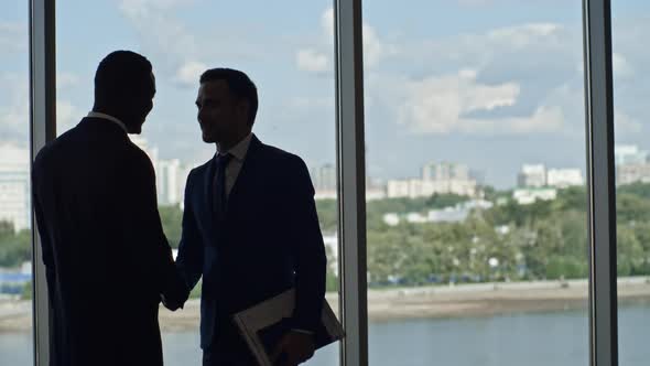 Silhouettes of Business Partners Shaking Hand in Office Center