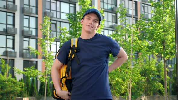 Portrait Smiling Man Courier Food Delivery Puts on Thermal Backpack Looks Camera