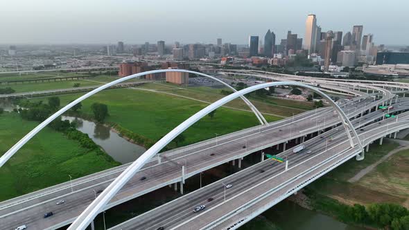 Arch and span of Margaret McDermott Bridge and Dallas skyline. I-30 traffic on interstate loop in Te