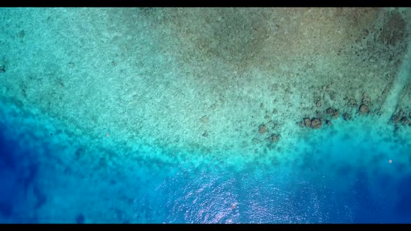 Aerial texture of tranquil bay beach holiday by blue green water and bright sandy background of a da