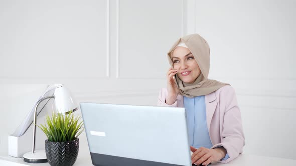 Attractive Relaxed Muslim Woman Is Talking Mobile Phone Sitting on Her Workplace