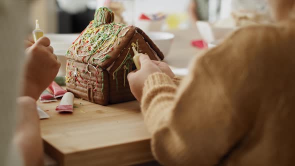 Detail video of children and mother decorating gingerbread house. Shot with RED helium camera in 8K.